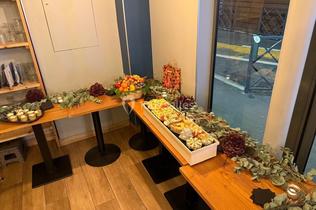 Buffet disposé sur des tables en bois avec des plats variés, des décorations végétales et une vue sur l'extérieur.