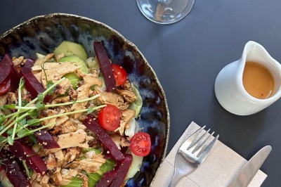 Salade composée de légumes frais, poulet effiloché et betteraves, avec une vinaigrette à part et des couverts sur une…