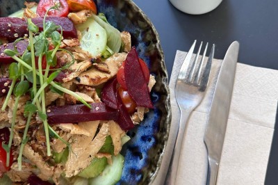Salade composée de légumes frais, poulet effiloché et betteraves, avec une vinaigrette à part et des couverts sur une…