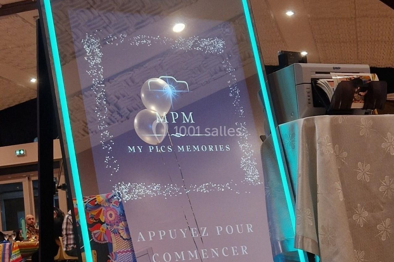 Borne photo interactive avec écran lumineux, installée dans une salle de réception au décor coloré.