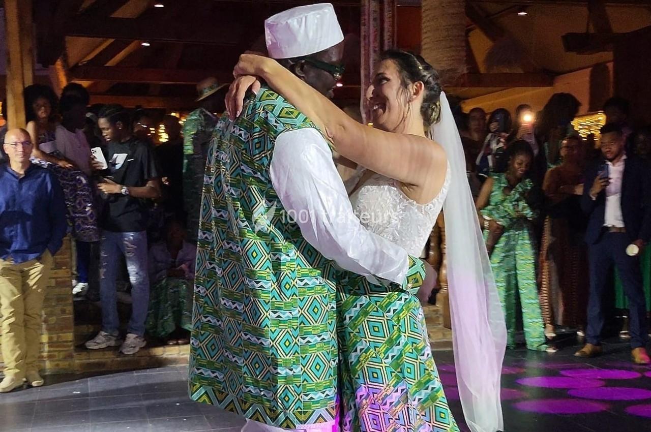 Un couple en tenue traditionnelle danse lors d'une réception de mariage, entouré d'invités.