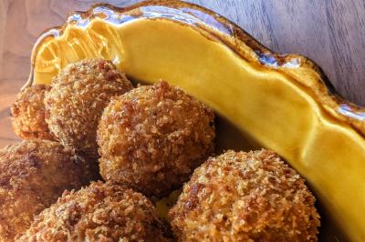 Une personne découpe un petit oignon sur une planche, entourée de légumes frais et d'herbes aromatiques.