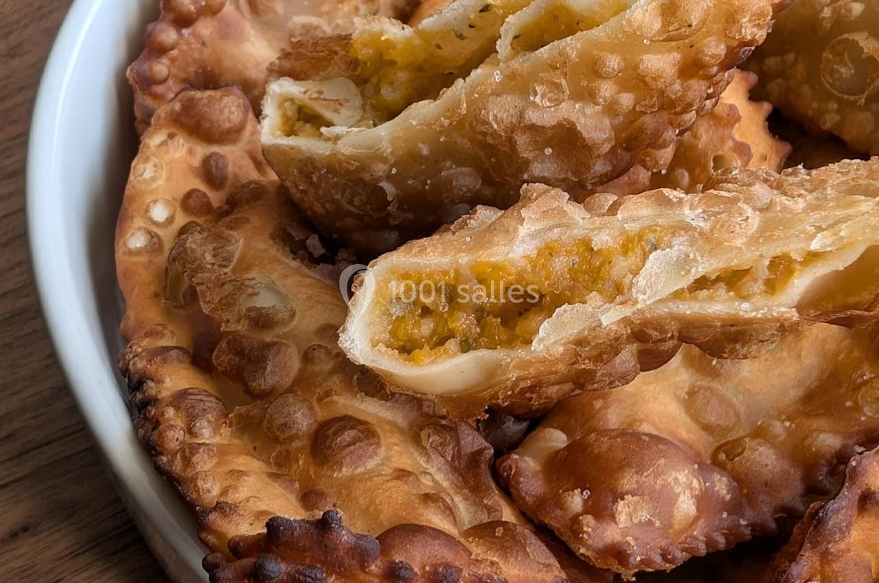 Assortiment de chaussons frits dorés, dont un ouvert révélant une farce épicée à base de légumes.