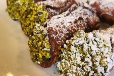 Une personne découpe un petit oignon sur une planche, entourée de légumes frais et d'herbes aromatiques.