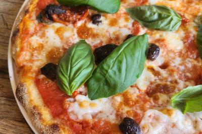 Une personne découpe un petit oignon sur une planche, entourée de légumes frais et d'herbes aromatiques.