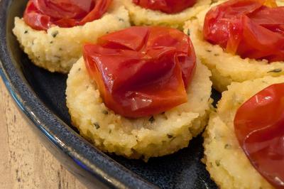 Une personne découpe un petit oignon sur une planche, entourée de légumes frais et d'herbes aromatiques.