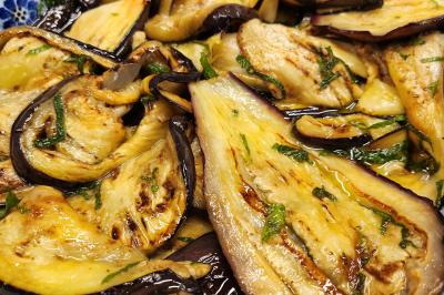 Une personne découpe un petit oignon sur une planche, entourée de légumes frais et d'herbes aromatiques.