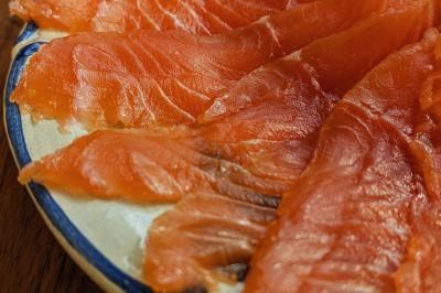Une personne découpe un petit oignon sur une planche, entourée de légumes frais et d'herbes aromatiques.