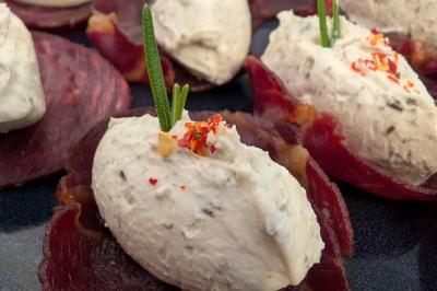 Une personne découpe un petit oignon sur une planche, entourée de légumes frais et d'herbes aromatiques.