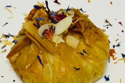 Tranches d'orange garnies de groseilles, pétales de fleurs, amandes effilées et feuilles de menthe dans une assiette.