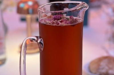 Tranches d'orange garnies de groseilles, pétales de fleurs, amandes effilées et feuilles de menthe dans une assiette.