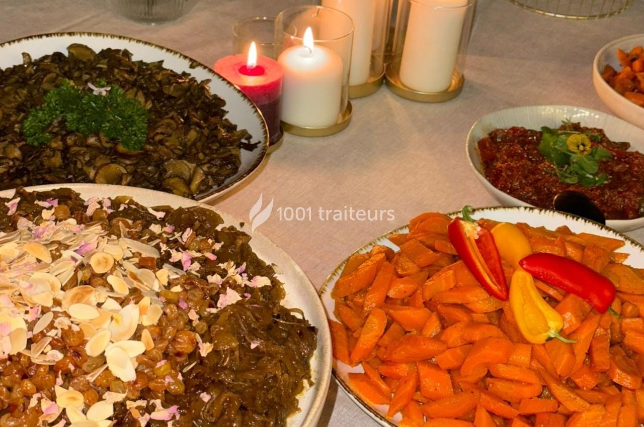 Assortiment de plats cuisinés comprenant des légumes, des amandes, des champignons et des bougies en arrière-plan.