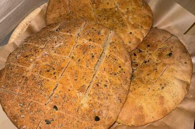 Tranches d'orange garnies de groseilles, pétales de fleurs, amandes effilées et feuilles de menthe dans une assiette.