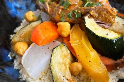 Tranches d'orange garnies de groseilles, pétales de fleurs, amandes effilées et feuilles de menthe dans une assiette.