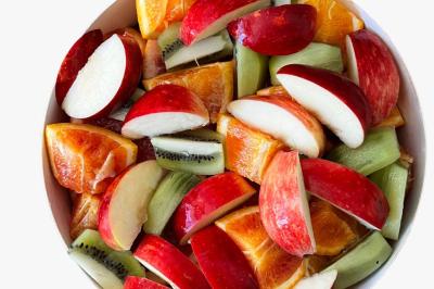 Tranches d'orange garnies de groseilles, pétales de fleurs, amandes effilées et feuilles de menthe dans une assiette.