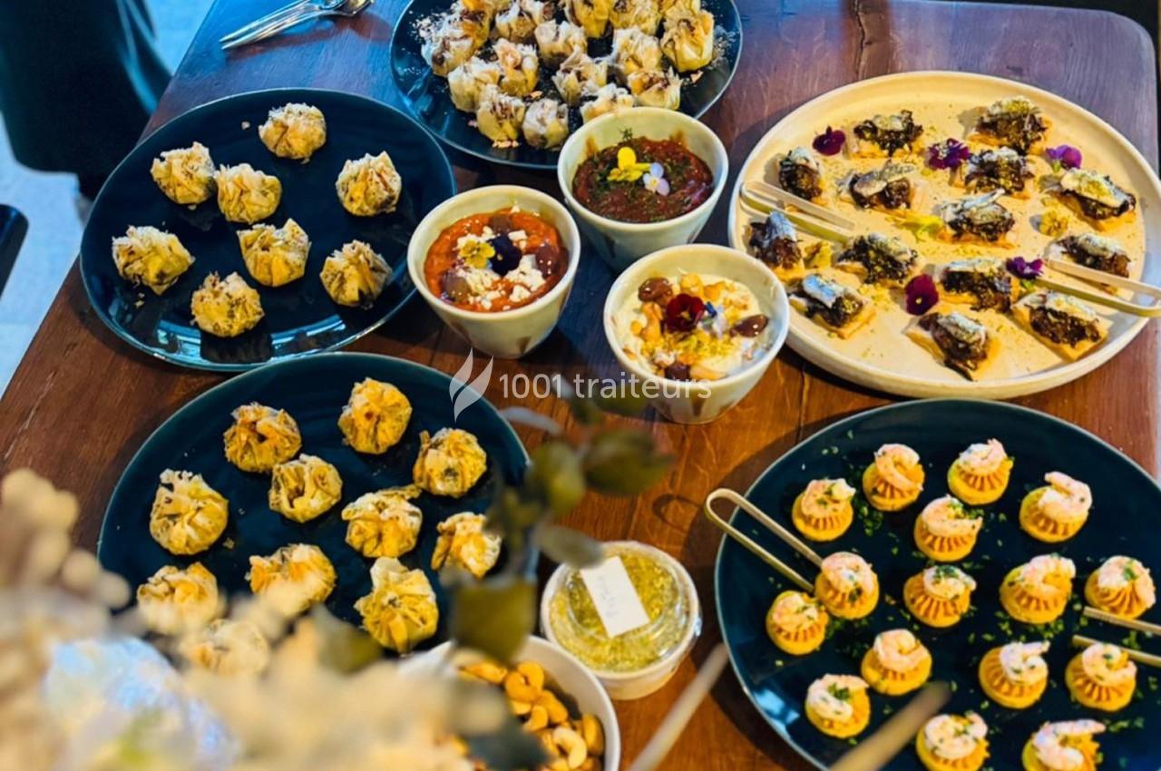 Plats variés de bouchées salées et sucrées présentés sur des assiettes et bols sur une table en bois.
