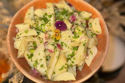 Tranches d'orange garnies de groseilles, pétales de fleurs, amandes effilées et feuilles de menthe dans une assiette.
