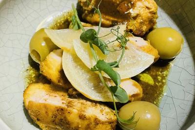 Tranches d'orange garnies de groseilles, pétales de fleurs, amandes effilées et feuilles de menthe dans une assiette.