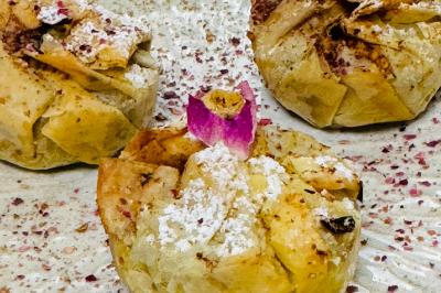 Tranches d'orange garnies de groseilles, pétales de fleurs, amandes effilées et feuilles de menthe dans une assiette.