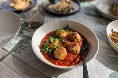 Tranches d'orange garnies de groseilles, pétales de fleurs, amandes effilées et feuilles de menthe dans une assiette.