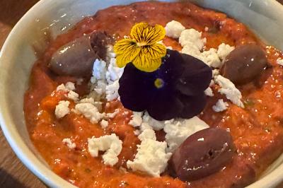 Tranches d'orange garnies de groseilles, pétales de fleurs, amandes effilées et feuilles de menthe dans une assiette.