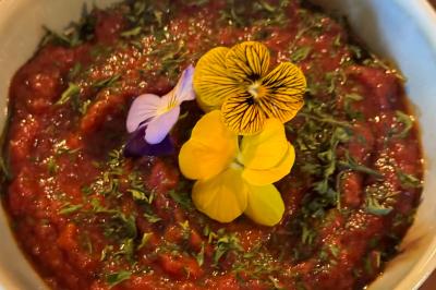 Tranches d'orange garnies de groseilles, pétales de fleurs, amandes effilées et feuilles de menthe dans une assiette.