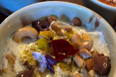 Tranches d'orange garnies de groseilles, pétales de fleurs, amandes effilées et feuilles de menthe dans une assiette.