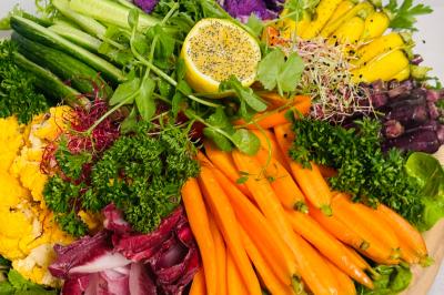 Tranches d'orange garnies de groseilles, pétales de fleurs, amandes effilées et feuilles de menthe dans une assiette.