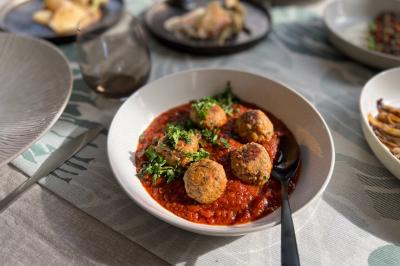 Tranches d'orange garnies de groseilles, pétales de fleurs, amandes effilées et feuilles de menthe dans une assiette.