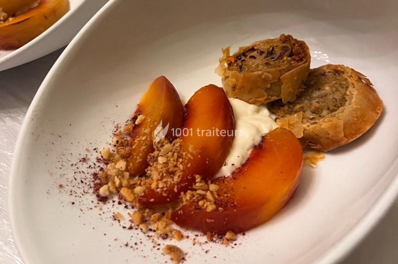 Tranches de pêche, crème, crumble et roulé feuilleté aux noix, présentés dans une assiette blanche.