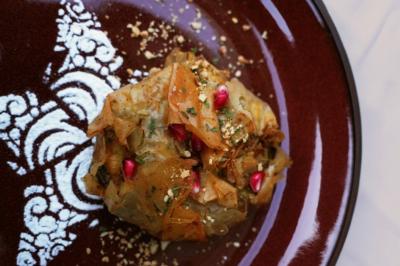 Tranches d'orange garnies de groseilles, pétales de fleurs, amandes effilées et feuilles de menthe dans une assiette.