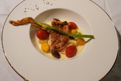 Tranches d'orange garnies de groseilles, pétales de fleurs, amandes effilées et feuilles de menthe dans une assiette.