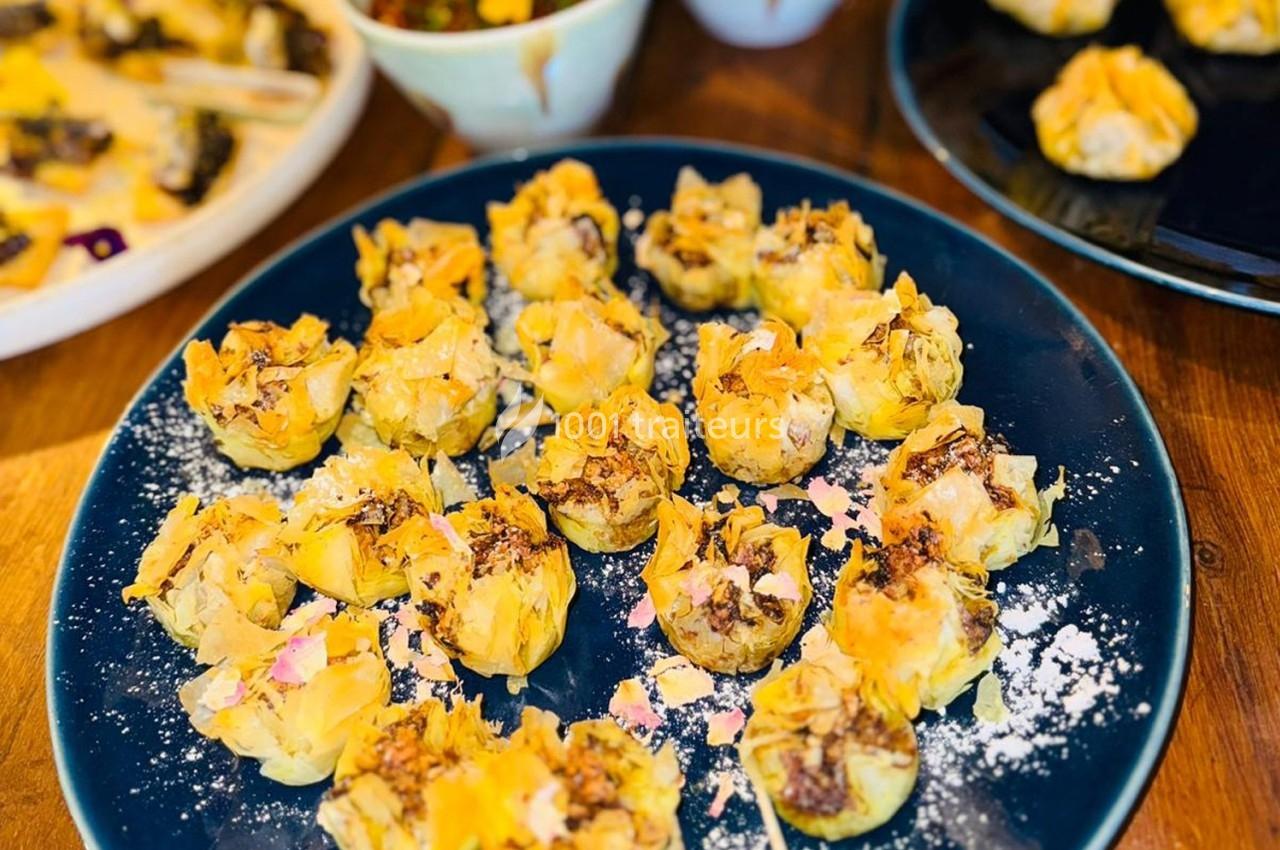 Assortiment de bouchées feuilletées garnies, présentées sur une assiette bleue avec une légère décoration sucrée.