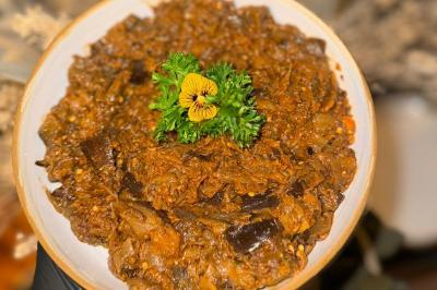 Tranches d'orange garnies de groseilles, pétales de fleurs, amandes effilées et feuilles de menthe dans une assiette.