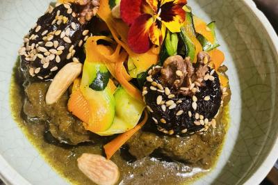 Tranches d'orange garnies de groseilles, pétales de fleurs, amandes effilées et feuilles de menthe dans une assiette.