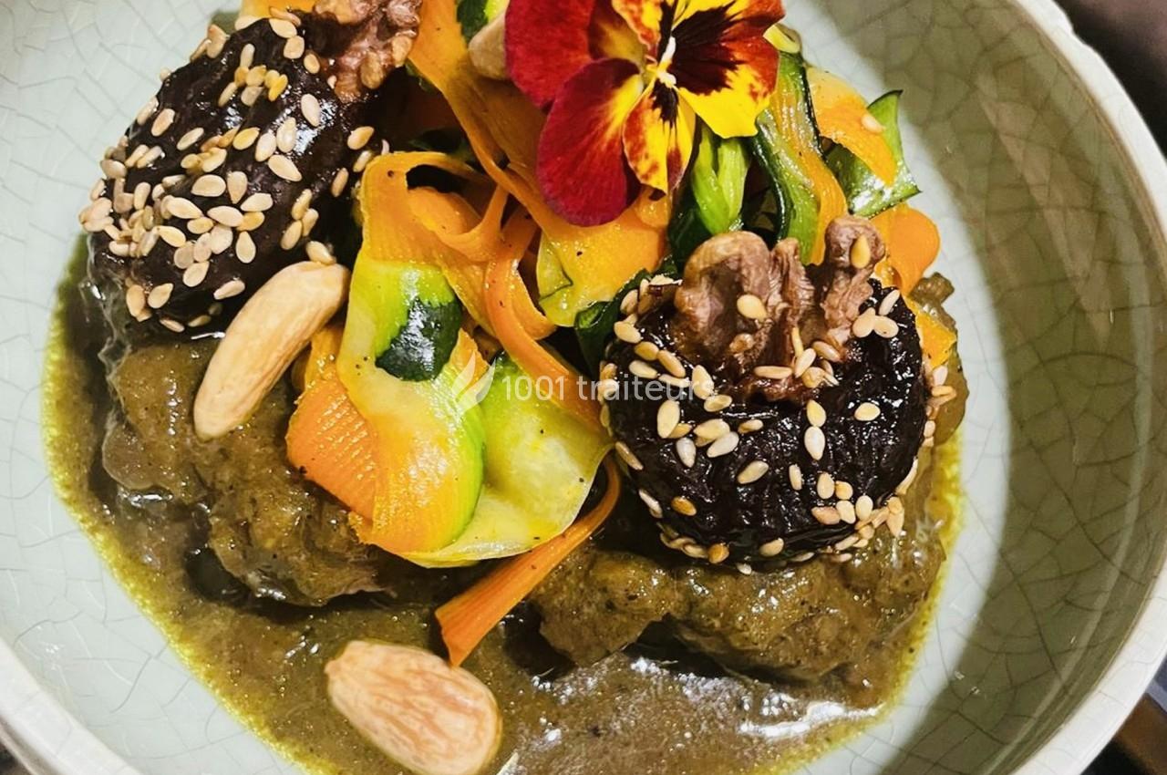 Assiette garnie de légumes colorés, pruneaux aux graines de sésame, noix et amandes, sur une sauce verte.