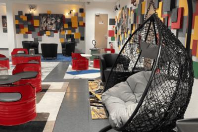 Accueil avec comptoir noir, décoration murale, tableau coloré, et éclairage au plafond dans un espace moderne.