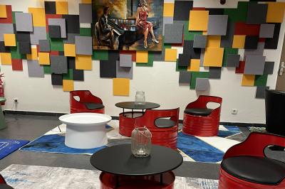 Accueil avec comptoir noir, décoration murale, tableau coloré, et éclairage au plafond dans un espace moderne.