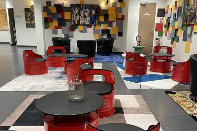 Accueil avec comptoir noir, décoration murale, tableau coloré, et éclairage au plafond dans un espace moderne.