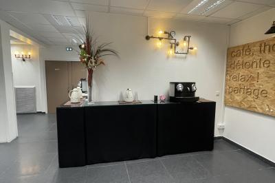 Accueil avec comptoir noir, décoration murale, tableau coloré, et éclairage au plafond dans un espace moderne.