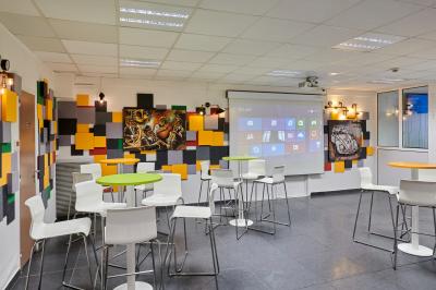 Accueil avec comptoir noir, décoration murale, tableau coloré, et éclairage au plafond dans un espace moderne.