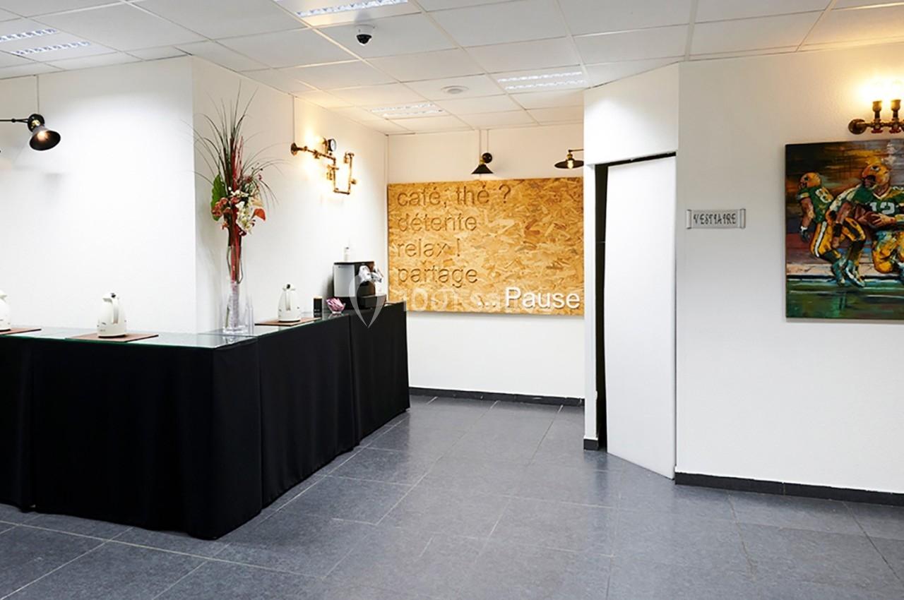 Espace de pause avec comptoir noir, décorations murales, tableau coloré et éclairage chaleureux.