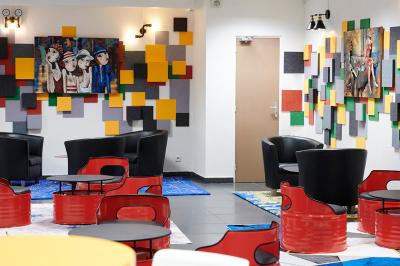 Espace de pause avec comptoir noir, décorations murales, tableau coloré et éclairage chaleureux.