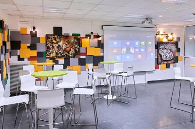 Espace de pause avec comptoir noir, décorations murales, tableau coloré et éclairage chaleureux.