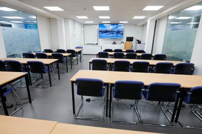 Espace de pause avec comptoir noir, décorations murales, tableau coloré et éclairage chaleureux.