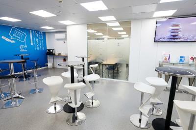 Espace de pause avec comptoir noir, décorations murales, tableau coloré et éclairage chaleureux.