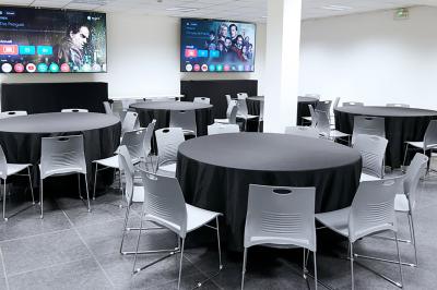 Espace de pause avec comptoir noir, décorations murales, tableau coloré et éclairage chaleureux.