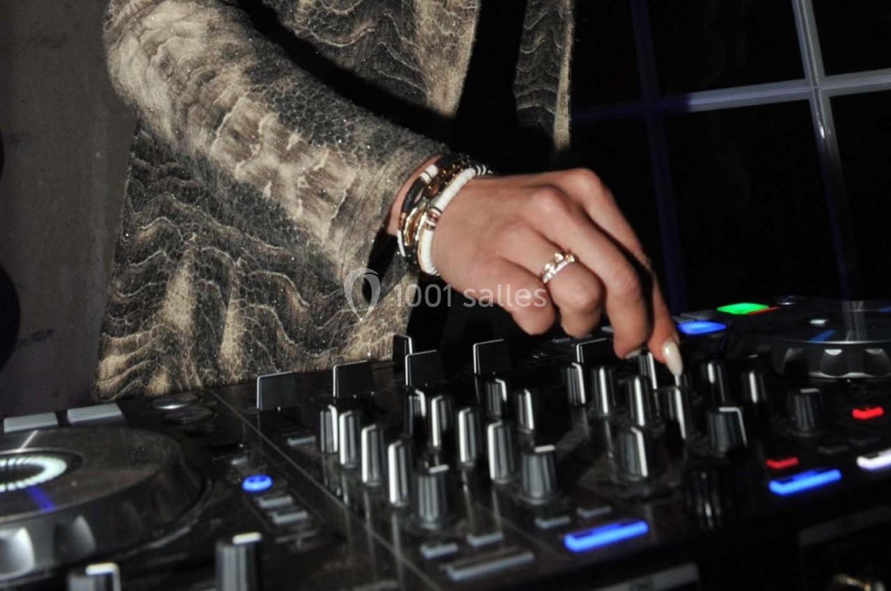 Main ajustant des commandes sur une table de mixage dans un environnement sombre.