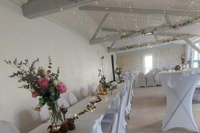 Femme concentrée, portant une robe claire, devant un mur en pierre texturée sous un éclairage violet.