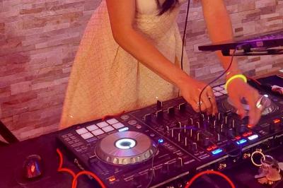 Femme concentrée, portant une robe claire, devant un mur en pierre texturée sous un éclairage violet.